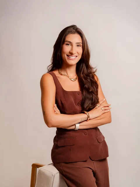 Natália de braços cruzados, sorrindo