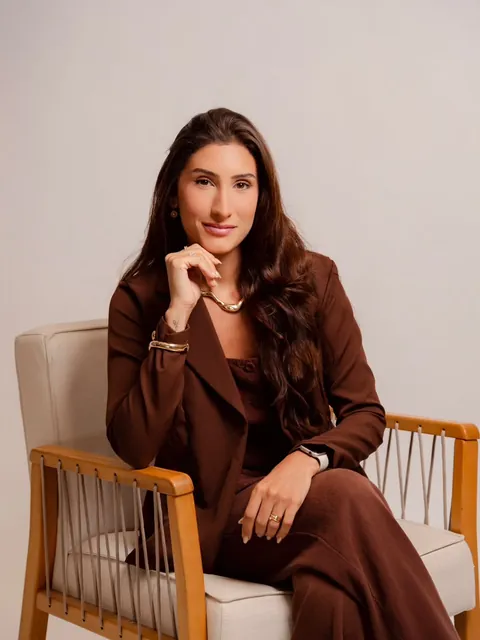 Natália sentada em uma poltrona, pensativa