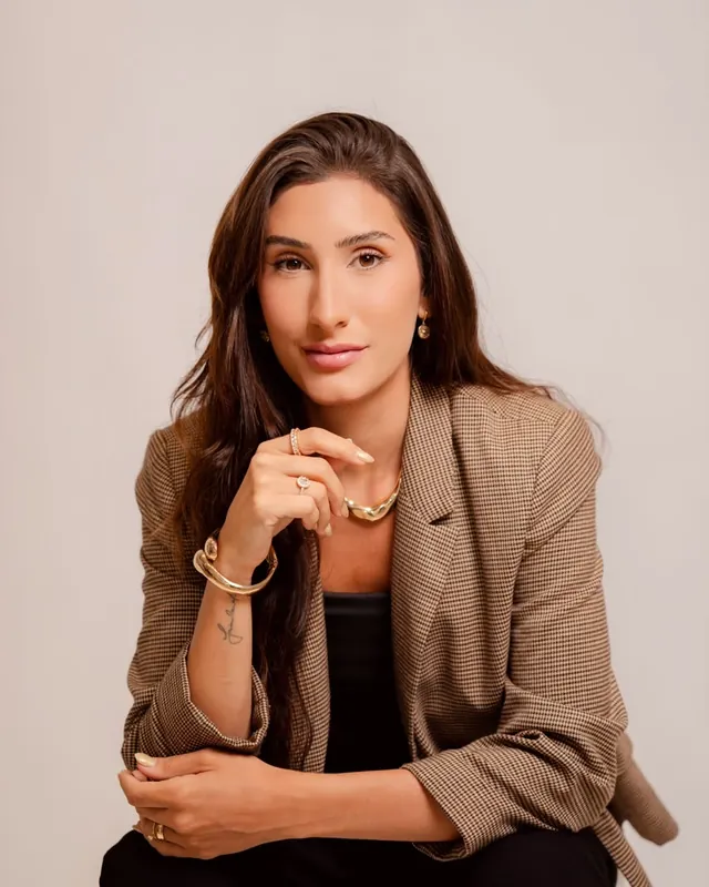 Natália Dadalto com expressão séria, a mão no queixo